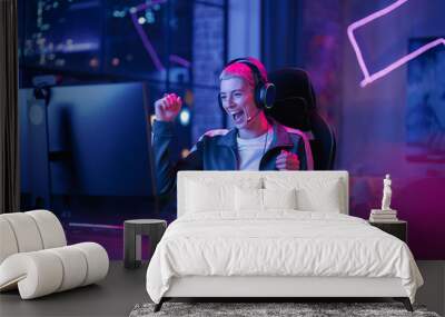 Successful Female Gamer Winning in Online Video Game on Computer. Portrait of Young Stylish Woman in Headphones Playing PvP Tournament with Other Players, Talking with Team on Microphone. Wall mural