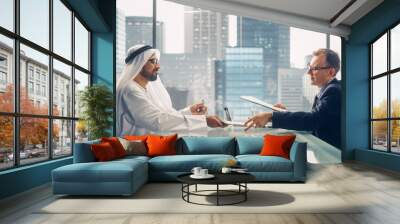 Two Businessmen with Different Nationalities Sitting in Office and Signing Contract. Arab Business Partner Make with Investor Financial Deal. Saudi, Emirati, Arab Businessman Concept. Wall mural