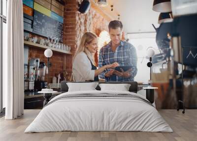 Two Diverse Entrepreneurs Have a Team Meeting in Their Stylish Coffee Shop. Barista and Cafe Owner Discuss Work Schedule and Menu on Tablet Computer. Young Female and Male Restaurant Employees. Wall mural