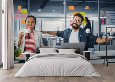 Two Happy Young Professionals in Office: Black Businesswoman and Hispanic Businessman Dance Together, Smile Looking at Camera, Sitting at Desk. Specialists Work in Creative Office, Celebrate Success Wall mural