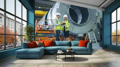 two heavy industry engineers stand in pipe manufacturing factory, use digital tablet computer, have  Wall mural