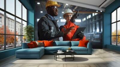 Two Heavy Industry Engineers Stand in Steel Metal Manufacturing Factory, Use Digital Tablet Computer and Have a Discussion. Black African American Industrial Specialist Talk to Female Technician. Wall mural