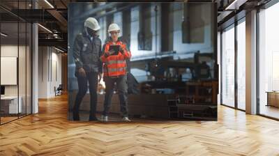 Two Heavy Industry Engineers Walk in Steel Factory, Use Tablet and Discuss Work. Industrial Worker Uses Angle Grinder in the Background. Black African American Specialist Talks to Female Technician. Wall mural