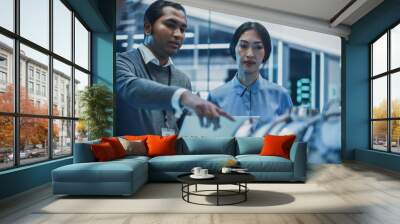 Two Multiethnic Employees Work in Modern Innovative Research Facility with a Futuristic Jet Engine. Engineer with a Laptop Explaining How the Prototype Motor Works to an Industrial Specialist. Wall mural