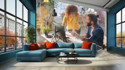 Two Stylish Employees Discussing Work-Related Projects on Computer in Creative Agency in Loft Office. Young Creative Man and Woman Talking About a Corporate Project Wall mural