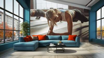 Two Young Fit Atletic Women Hold a Plank Position in Order to Exercise Their Core Strength. They are Exhausted and Struggling with Training. They Workout in a Loft Gym. Wall mural