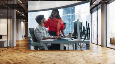 Two Young Indian Financial Advisers Having a Conversation About Stock Market Strategy Next to a Computer in a Modern Company. South Asian Managers Work in a Banking Research and Development Center Wall mural