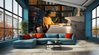 University Library: Gifted Black Girl uses Laptop, Writes Notes for the Paper, Essay, Study for Class Assignment. Students Learning, Studying for Exams College. Side View Portrait with Bookshelves Wall mural