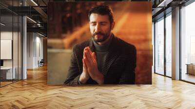 Young Christian Man on his Knees in Church, with Folded Hands He Seeks Guidance From Faith and Spirituality while Praying. Religious Believer in the Power and Love of God Wall mural