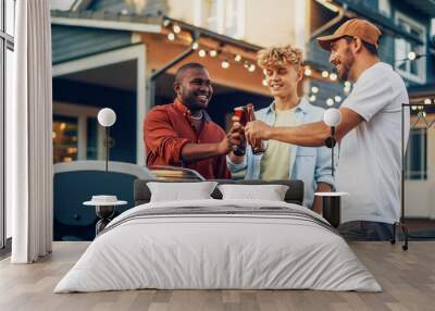 Young Man in a Cap Showing Off His Modern Fire Grill to Two Diverse Mates at a Garden Barbecue Party. Friends Talking, Relaxing, Drinking Beers at a Backyard Home Gathering. Wall mural