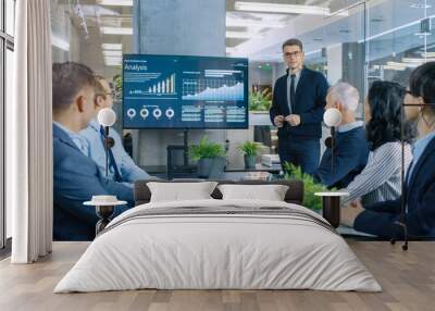 Young Stock Trader Shows to the Executive Managers Cryptocurrency and Trade Market Correlation Pointing at the Wall TV. Wall mural