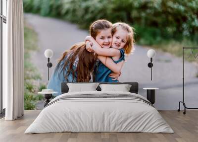 two qute sisters with peonies. Concept of happy family and love between sisters Wall mural