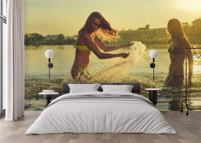 picture of two beautiful girls best friends having fun and splashing water at sunset on sunny copy s Wall mural