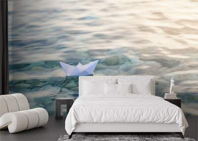 Alone paper boat floats in waves on the water. Wall mural