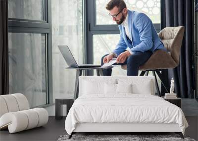 business caucasian man sitting in working with laptop in office near window Wall mural