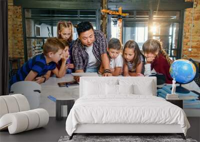 Creative school children with young asian teacher study an electronic constructor with fan and turn on flashlight. Creative pupils with teacher working on the tech project at school. Wall mural