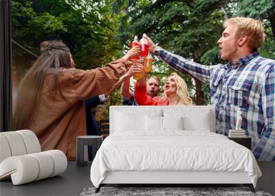 Friends clinking glass bottles with alcohol cocktails, drinking beer and enjoying evening birthday party celebration on weekend. Wall mural