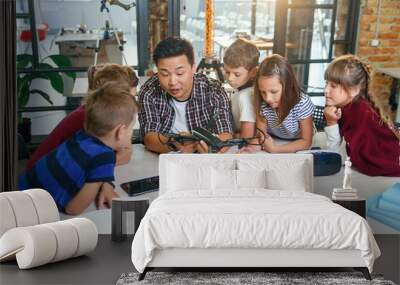 in physics and mechanics lesson young asian teacher demonstrates quadcopter for caucasian pupils at  Wall mural