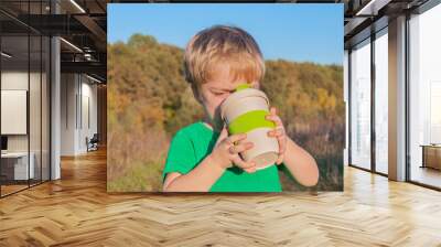 The boy travels near the forest. Sunset light. He drinks from the eco cup Wall mural