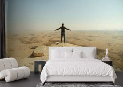 Alone man in desert stand on the cliff and spread his arms for a freedom Wall mural