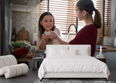 Caucasian teenager girl cooking dinner with mother at home Wall mural