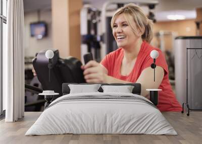 happy woman riding on exercise bike at the gym Wall mural