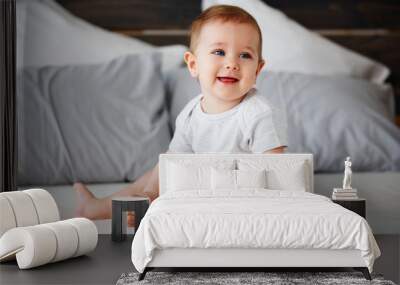 Smiling baby sitting on bed Wall mural