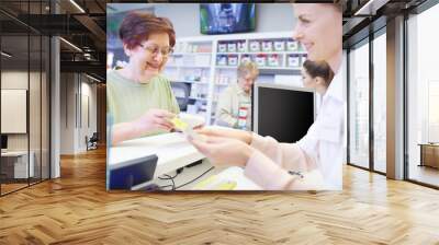 Young pharmacist explaining dose to female senior . Wall mural