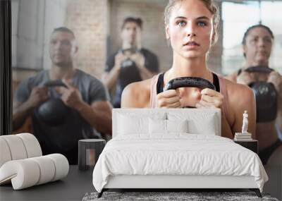 Fitness, exercise and woman with kettlebell in a gym for a strength training challenge. Sports, energy and female athlete doing a workout with weights with her friends or community in wellness center Wall mural