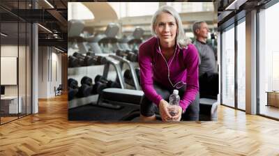 Stay focused, stay fit. a senior group of people working out together at the gym whilst a mature woman takes a break. Wall mural