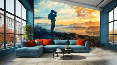 Photographer at sunset on mountain peak. Wall mural