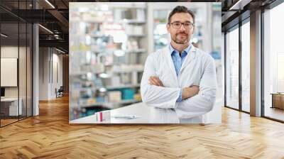 Healthcare, crossed arms and portrait of a male pharmacist standing in a pharmacy clinic. Pharmaceutical, medical and mature man chemist with confidence by the counter of medication store dispensary. Wall mural