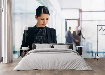 Working hard is good, but working smart is better. an attractive young businesswoman using a digital tablet in an office with her colleagues in the background. Wall mural