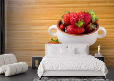 Fresh juicy strawberries in a bowl on a bamboo mat. Close-up image. Wall mural