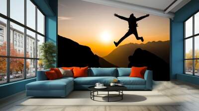 Achievement of the goal: Young sporty happy man jumps in the sunset at the peak of a mountain Wall mural