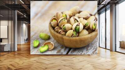 Pistachios with and without shell in bamboo bowl on rustic wooden surface
 Wall mural