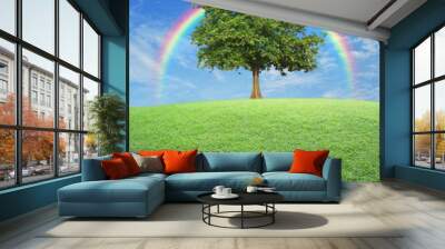 Big tree with green grass field over rainbow and blue sky, natur Wall mural