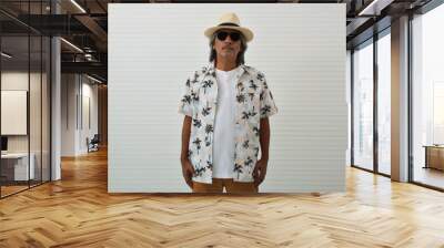 Confident senior traveler asian man wearing straw hat, sunglasses, summer shirt and brown shorts standing over white wall background, Business summer holiday concept Wall mural