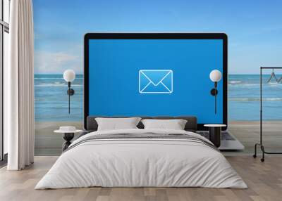 email flat icon with modern laptop computer on wooden table over tropical sea and blue sky with white clouds, Business contact us online concept Wall mural