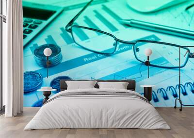 Glasses, coins, calculator and pen on financial chart and graph, Business investment concept Wall mural