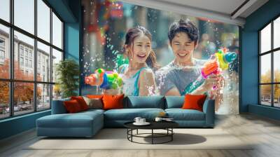 Happy traveler asian man and woman wearing summer shirt holding colourful squirt water gun over blur city, Water festival holiday concept Wall mural