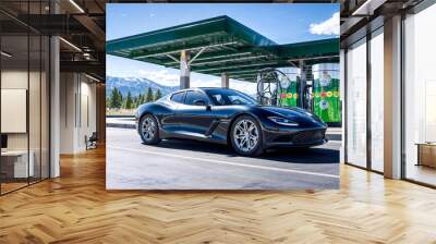 Black sports car at a hydrogen fueling station surrounded by snow-capped mountains Wall mural