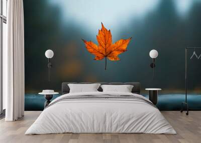 Bright orange maple leaf suspended in mid-air against a blurred autumn forest backdrop Wall mural