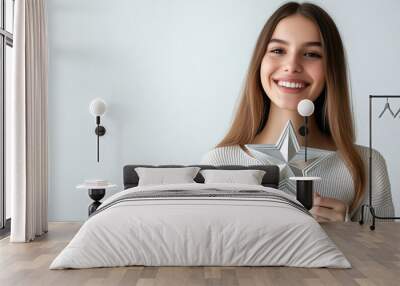 A happy young woman presenting a 3D star icon in silver color Wall mural