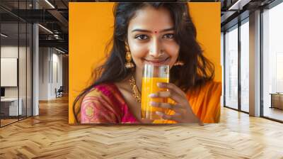 Happy Indian woman wearing saree, drinking juice Wall mural