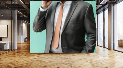 Senior Arabian Businessman in Suit Engaged in Phone Call with Mint Background. Wall mural