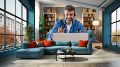 Business man with headsets working on laptop at home office. Customer service assistant working in office. Man operator working with headsets and laptop at telemarketing customer service. call center Wall mural