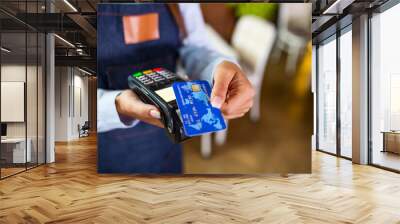 Contactless payment concept, female holding credit card near nfc technology on counter, client make transaction pay bill on terminal rfid cashier machine in restaurant store, close up view Wall mural