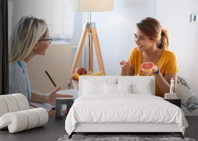 Female nutritionist giving consultation to patient. Making diet plan. Young woman visiting nutritionist in weight loss clinic Wall mural