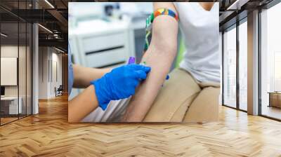 Medical technologist doing a blood draw services for patient. lab assistant with sterile rubber gloves taking blood sample from patient. Wall mural